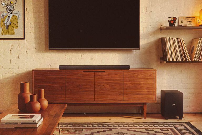A soundbar under a TV with a subwoofer.